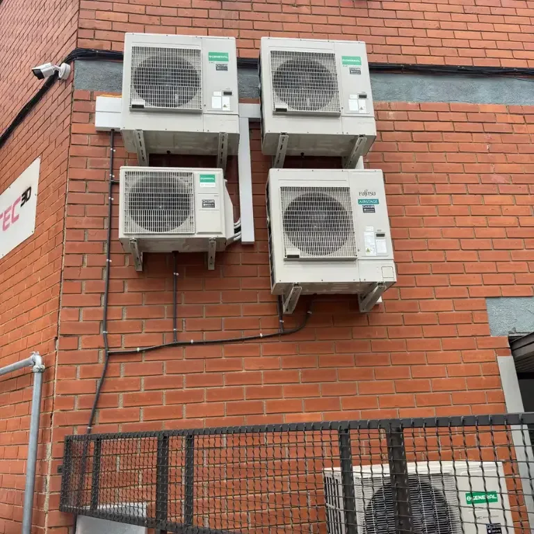 Cuatro unidades exteriores de aire acondicionado expuestas en fachada sin protección.